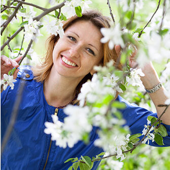 a-smiling-woman-is-walking-at-apple-tree-garden-in-springtime